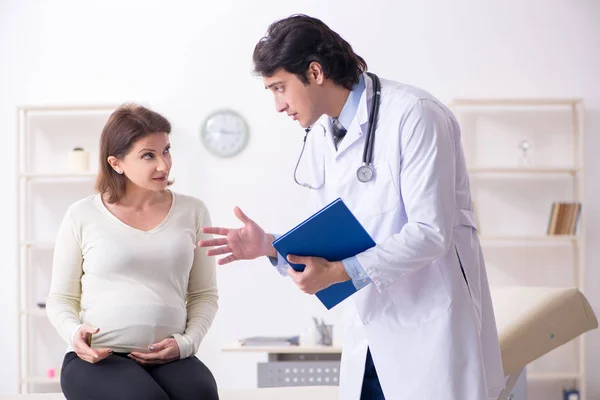 Velha mulher grávida visitando jovem médico masculino — Fotografia de Stock