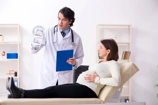 Vieja embarazada visitando joven médico masculino — Foto de Stock