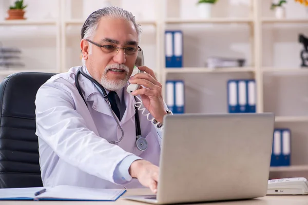 Klinikte çalışan yaşlı erkek doktor. — Stok fotoğraf