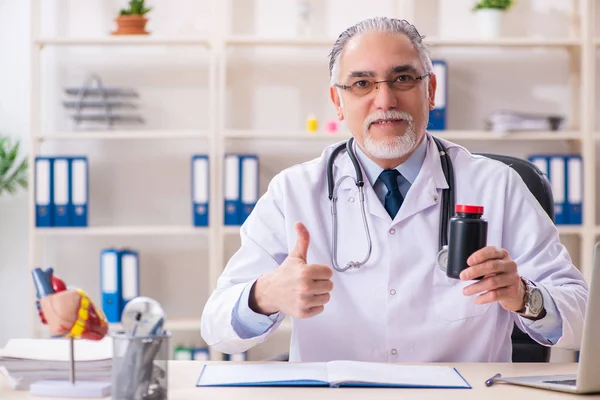 Åldrad manlig läkare som arbetar på kliniken — Stockfoto