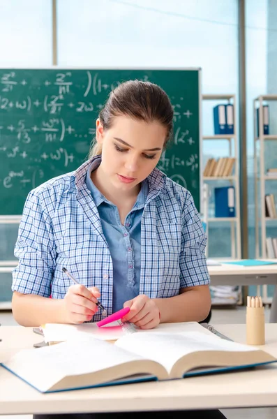 Vrouwelijke student met vele boeken die zitten in de klas — Stockfoto