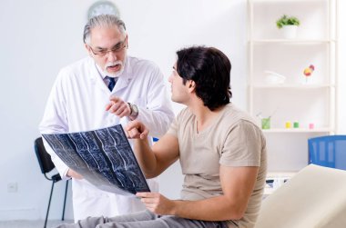 Genç adam yaşlı erkek doktor radyoloğu ziyaret ediyor. 