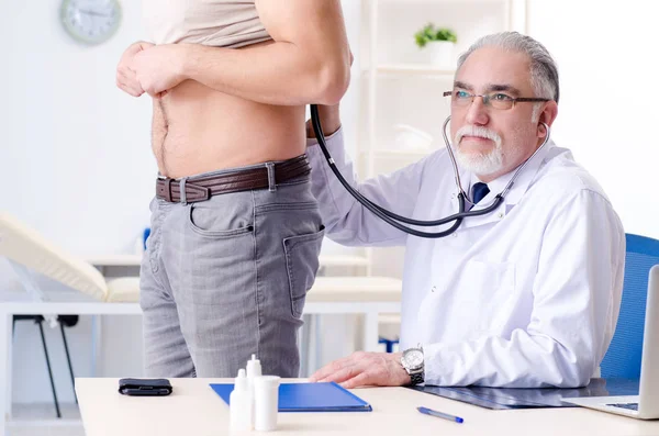 Joven paciente masculino visitando a viejo médico —  Fotos de Stock