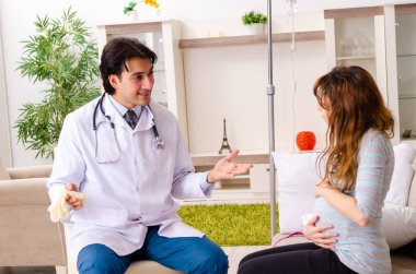 Genç, yakışıklı doktor hamile kadını ziyaret ediyor. 