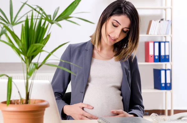Młoda pracownica w ciąży pracująca w biurze — Zdjęcie stockowe