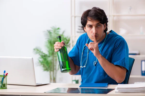 Young male doctor drinking in the office — Stock Photo, Image