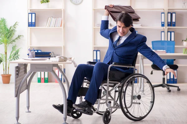 Young male employee in wheelchair working in the office