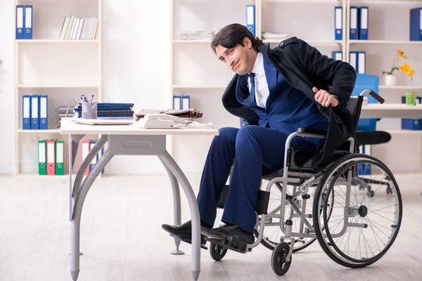 Young male employee in wheelchair working in the office