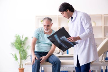 Yaşlı adam genç erkek doktoru ziyaret ediyor. 