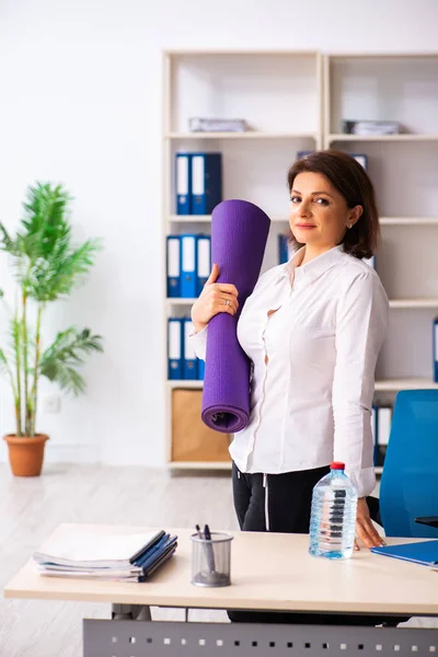 Empleada de mediana edad haciendo ejercicios en la oficina —  Fotos de Stock