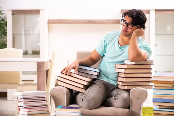 Studente maschio con molti libri a casa — Foto Stock