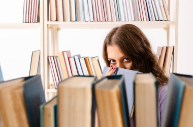 Genç kız öğrenci kütüphanede sınava hazırlanıyor. 