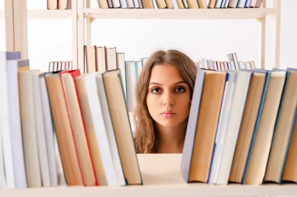 Jonge vrouwelijke student bereidt examens in de bibliotheek voor — Stockfoto