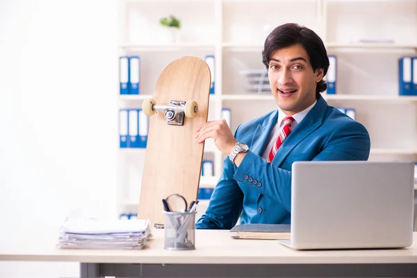 Young handsome businessman with longboard in the office — Stock Photo, Image