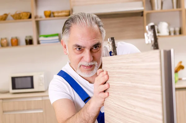 Aged contractor repairman working in the kitchen — Stock Photo, Image