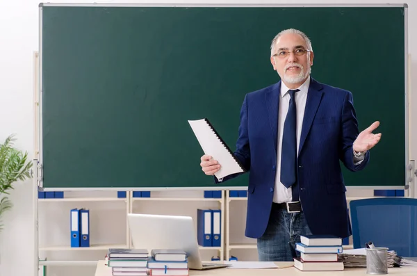 Aged male teacher in front of chalkboard — Stock Photo, Image
