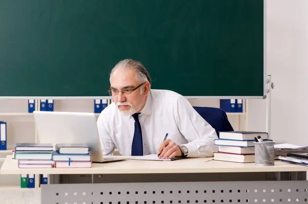 Aged male teacher in front of chalkboard — Stock Photo, Image