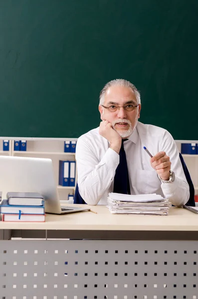 Aged male teacher in front of chalkboard — Stock Photo, Image