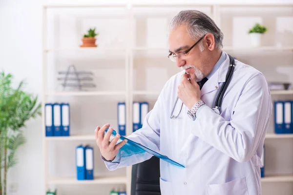 Klinikte çalışan yaşlı erkek doktor. — Stok fotoğraf