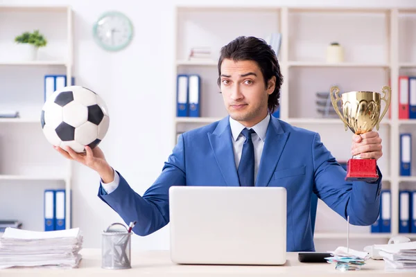 Jovem empresário bonito com bola de futebol no escritório — Fotografia de Stock