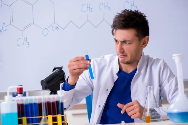 Młody chemik siedzi w laboratorium — Zdjęcie stockowe