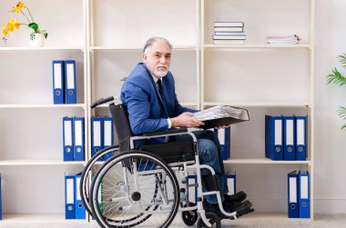 Ofiste çalışan yaşlı tekerlekli sandalyeliler. 