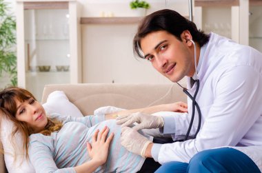Genç, yakışıklı doktor hamile kadını ziyaret ediyor. 