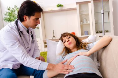 Genç, yakışıklı doktor hamile kadını ziyaret ediyor. 