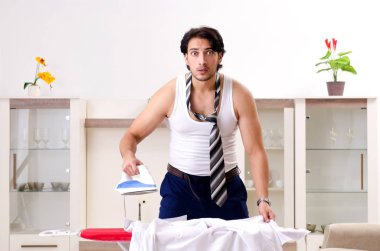 Genç adam yatak odasında ütü yapıyor.