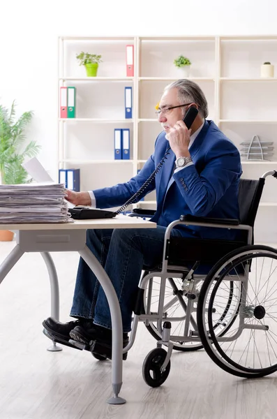 Employé âgé en fauteuil roulant travaillant au bureau — Photo