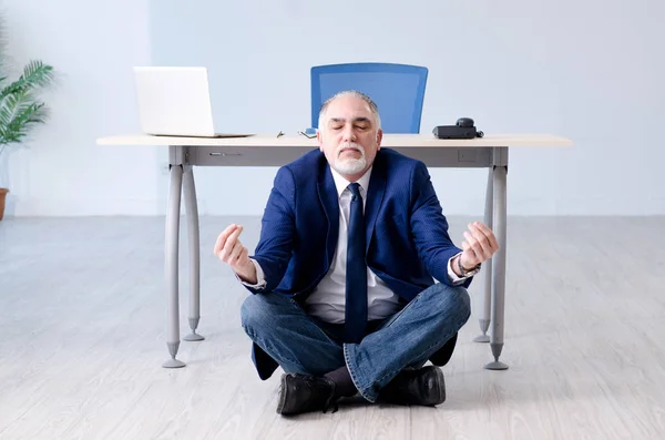 Betagter Geschäftsmann macht Yoga-Übungen im Büro — Stockfoto