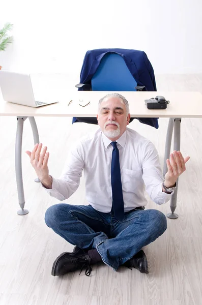 Homem de negócios envelhecido fazendo exercícios de ioga no escritório — Fotografia de Stock