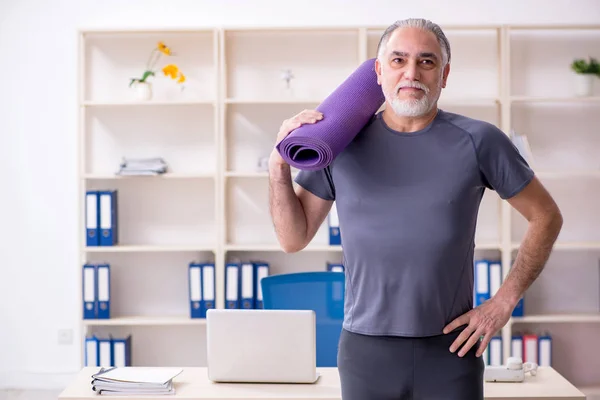 White bearded old man employee doing exercises in the office — Stock Photo, Image