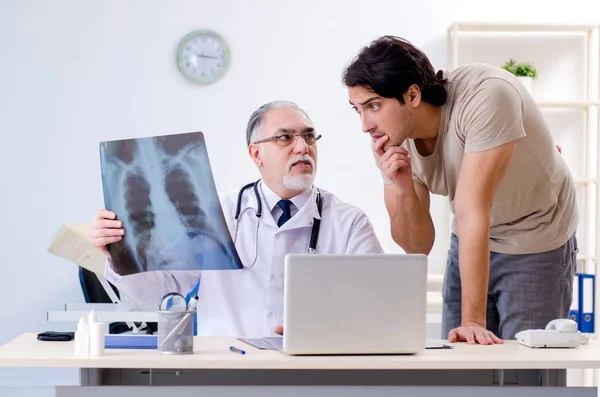 Hombre joven visitando viejo médico radiólogo — Foto de Stock