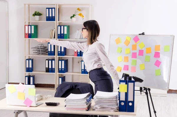 Joven empleada haciendo ejercicios en el lugar de trabajo — Foto de Stock