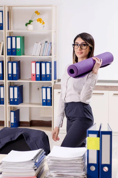 Mladá zaměstnankyně dělá cvičení na pracovišti — Stock fotografie