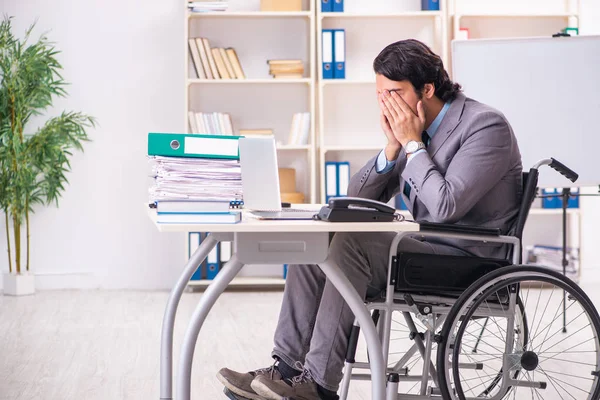 Young handsome employee in wheelchair at the office