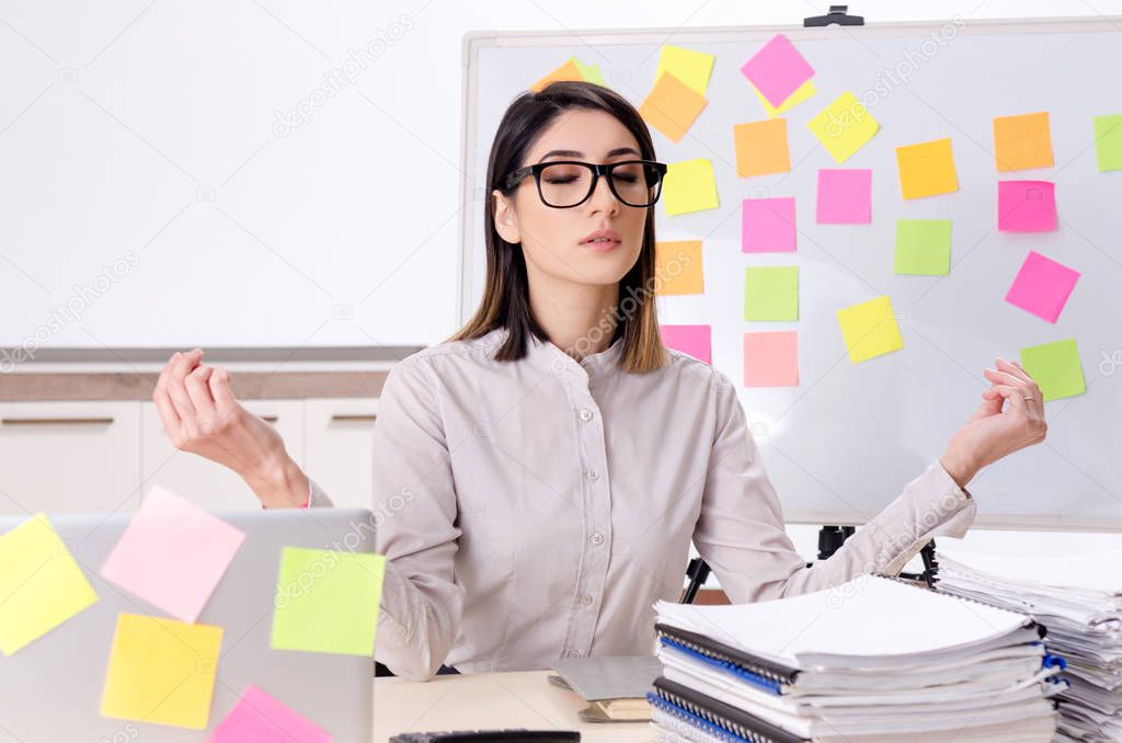 Young female employee doing exercises at workplace 