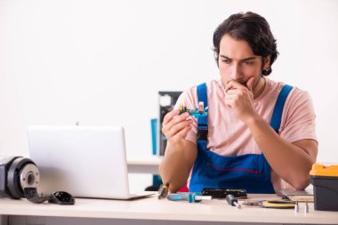 Genç bir erkek müteahhit bilgisayar tamir ediyor.  