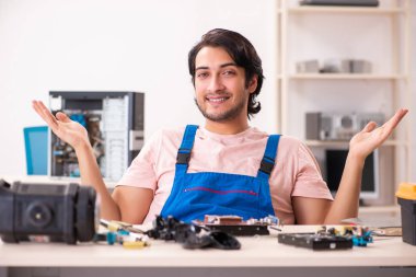 Genç bir erkek müteahhit bilgisayar tamir ediyor.  