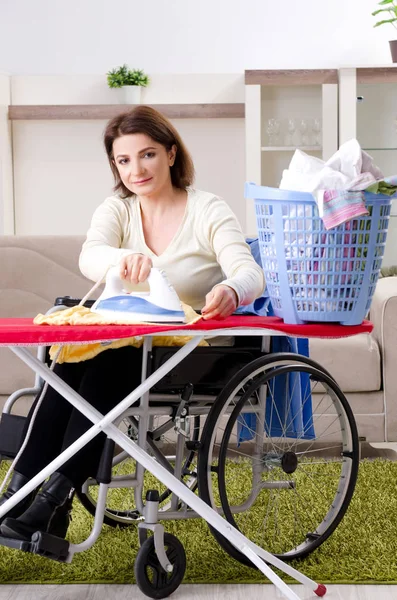 Vrouw in rolstoel strijken thuis — Stockfoto