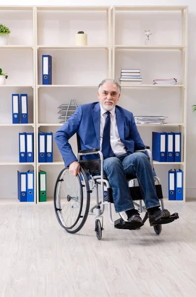 Empleado anciano en silla de ruedas que trabaja en la oficina — Foto de Stock