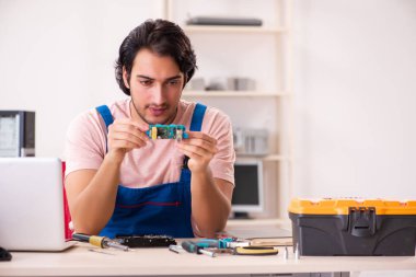 Genç bir erkek müteahhit bilgisayar tamir ediyor.  