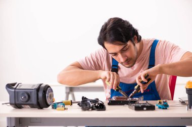 Genç bir erkek müteahhit bilgisayar tamir ediyor.  