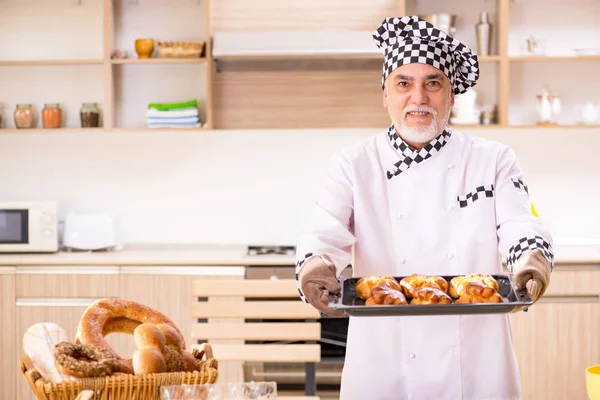 Old male baker working in the kitchen