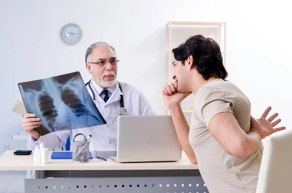 Jovem visitando velho médico radiologista masculino — Fotografia de Stock