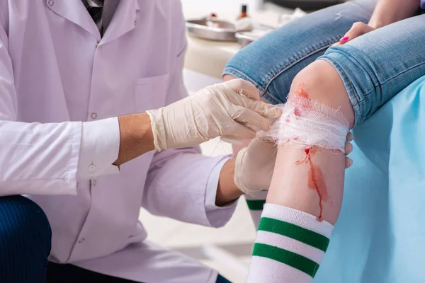 Leg injured young woman visiting male doctor — Stock Photo, Image