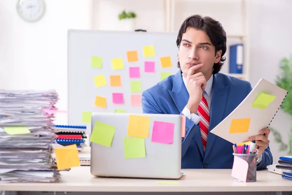 Young male handsome employee in conflicting priorities concept — Stock Photo, Image