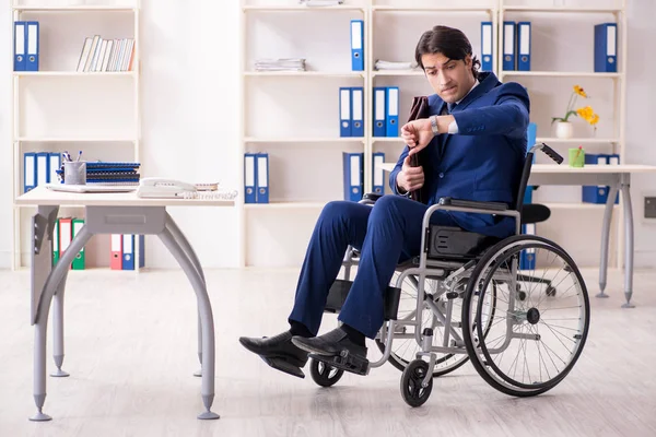 Młody mężczyzna na wózku inwalidzkim pracujący w biurze — Zdjęcie stockowe