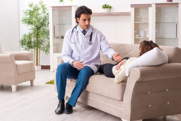 Jovem médico bonito visitando paciente feminino em casa — Fotografia de Stock